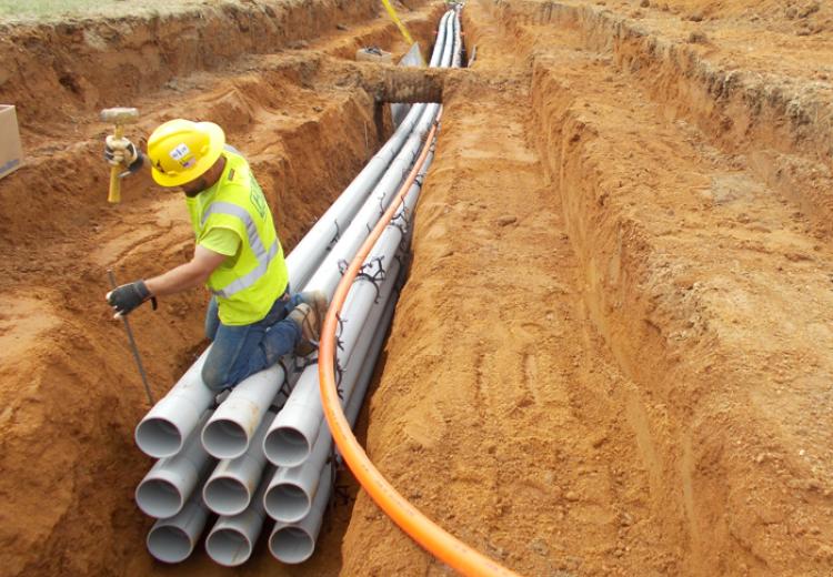 APG Electrical Distribution System conduit in trench with worker